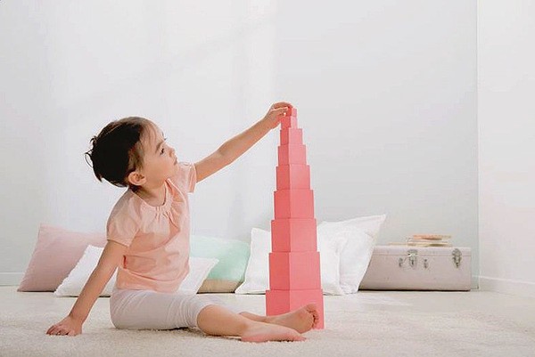 Enfant découvrant la Tour Rose en bois naturel, matériel emblématique de la méthode Montessori